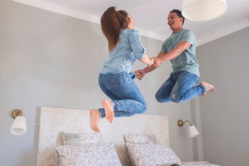 Young couple love life together at home and jump in the air in the bedroom - new house buy concept...