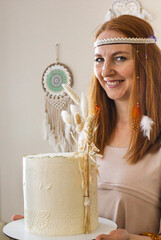 Happy elegant woman posing with tasty fresh cake cream beige decorated in boho scandi style