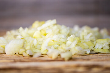 Detail of chopped onion placed on dark wooden desk. Preparation of cooking. Fresh, diet and healthy vegetable.