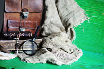 Old leather bag with a magnifying glass on a brown traveler wooden table background with copy space.
