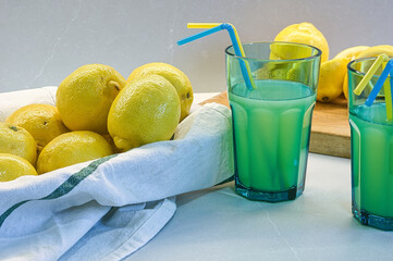 Bodegón de vasos grandes y azules con zumo de limón sobre una encimera de cocina gris clarito y...