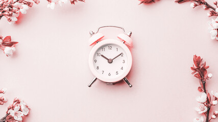 Spring border, spring blossom and April floral nature with alarm clock on pink background. Branches of blossoming apricot macro soft focus. Easter and spring greeting cards, copy space. Springtime.