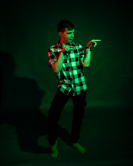 Portrait of a guy in a plaid shirt with red and green light on a black background