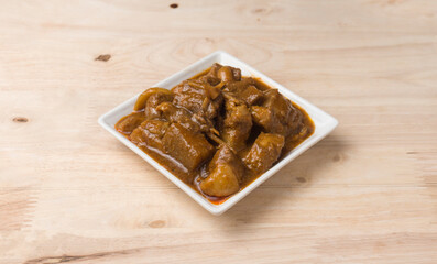 Kaeng hang le is a Northern Thai heavy curry with pork belly on wooden table.
