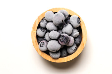 Frozen blueberries in wooden bowl isolated on white background.