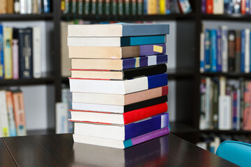 A stack of books in a large library selected by the reader lies on table