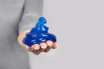 Hand with blue slime toy on grey background