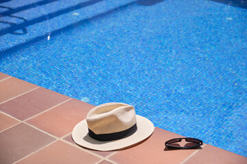 Fototapeta na wymiar hat and sunglasses on the edge of a swimming pool