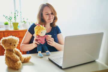 Kindergarten teacher in front of laptop having video conference chat with children