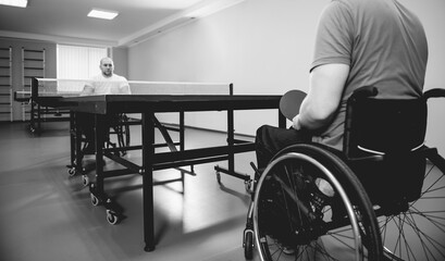 Adult disabled men in a wheelchair playing table tennis