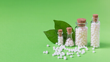 Bottles with homeopathic globules on a green background. Homeopathic medicine.
