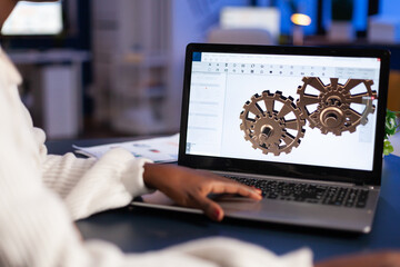 Close up of mechanical gears while engineer working with software for mechanism design. Freelancer...