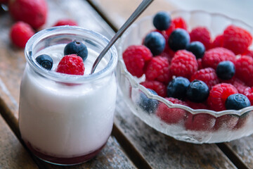 yoghurt with raspberries and blueberries on wooden background