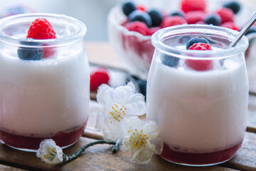 yoghurt with raspberries and blueberries on wooden background