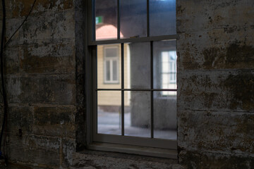 Fototapeta na wymiar Interior view of a window with small glass panes and view on old warehouse 