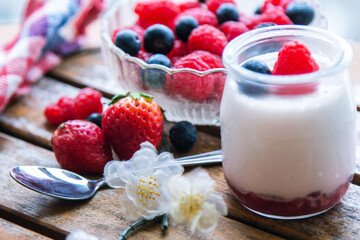 yoghurt with raspberries and blueberries on wooden background