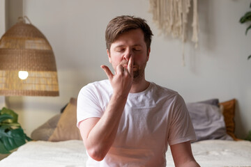Caucasian mature man practicing yoga sitting, making Alternate Nostril Breathing