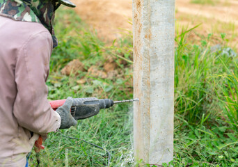 Obraz premium Workers drill cement columns to install support metal sheet.
