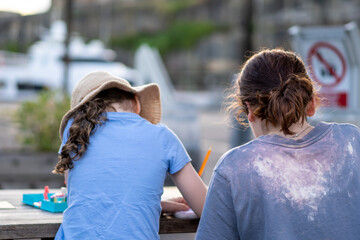 two children siting at table, drawing and doing arts and crafts together