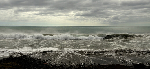 Beach shore, sea with waves and covered sky, coast of Jandia, Fuerteventura island