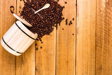 Coffee wooden barrel, roasted coffee beans on wooden background, coffee spoon, top view, copy space...