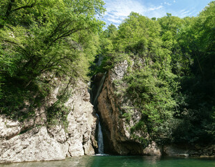 Fototapeta na wymiar A beautiful waterfall in a mountain gorge in the Caucasus. Agura waterfall. Sochi, Russia.