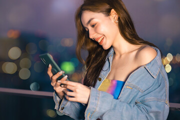 Obraz premium Portrait of smiling pretty young woman using phone on rooftop city bangkok.Female using mobile phone make vlog and live in social media .