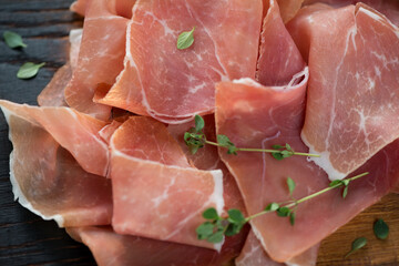 Closeup of jamon slices or spanish dry-cured ham and thyme, selective focus, studio shot