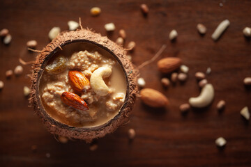 Close-up of Creamy Sabudana Kheer Garnished with dry fruits. Indian delicious dessert. Served in the coconut shell. Front view on wooden background.