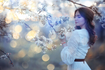 spring portrait of an adult happy woman in a blooming garden, sun rays and glare, april flowers girl