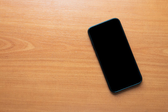 with black screen on a wooden background
smart cell phone.
tectology concept.
white screen for mackup app