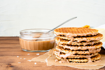 Traditional local authentic Dutch Netherlands sweet fresh homemade tasty stack brown golden waffle melt salted caramel honey syrup for dessert in cafe with hot warm coffee milk tea call Stroopwafel