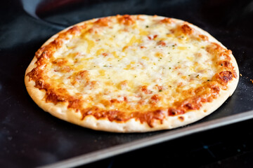 Close up and selective focus of a home cooked thin crust four cheese pizza straight from the oven on a baking mat