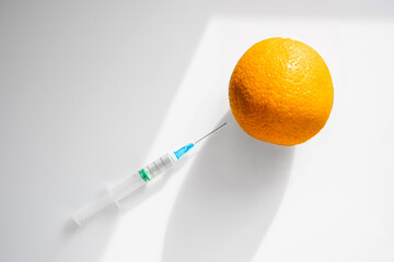 laboratory assistant injects chemicals with a syringe into an orange. fruits are processed for...