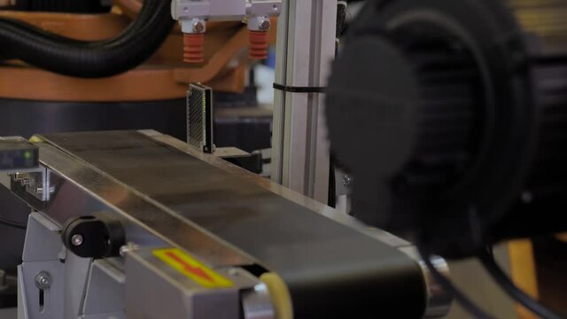 Pick and place robotic arm manipulator moving plastic detail on conveyor belt at modern robot trade show, exhibition - close up. Industrial, ai, manufacturing, automated technology concept