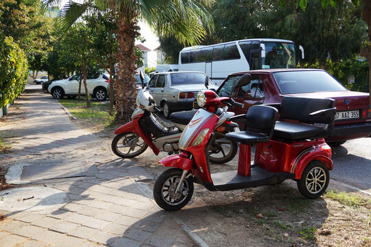 Side / Turkey - October 17 2019: Tricycle and motorcycle are standing near the road waiting for the owners. Convenient and inexpensive transport for moving around the city in warm summer weather.