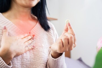 woman taking medicine for GERD, having problem with heartburn from acid reflux disease, discomfort...