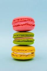 three multicolored macaron cakes on a blue paper background