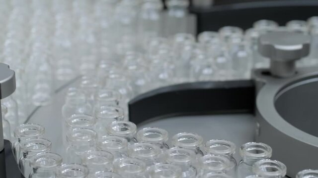 Conveyor belt with empty medical injection glass vials - pharmaceutical automatic production line. Medicine, manufacturing and automated pharma technology equipment concept