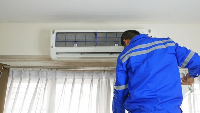 The service technician is washing the air conditioning system by removing the cover to spray water to clean the inside of the air conditioner.