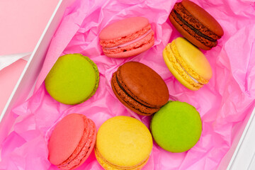 macarons cakes on a cardboard box in a pink paper background