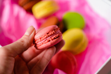 hand holds pink macaron cake in a pink paper background