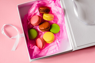 macarons cakes on a cardboard box in a pink paper background