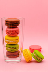 several color macaron cakes in a glass cup on a pink background