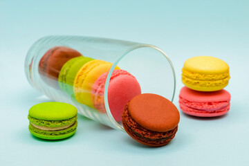several multicolored macaron cakes in a glass cup on a blue background