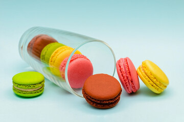 several multicolored macaron cakes in a glass cup on a blue background