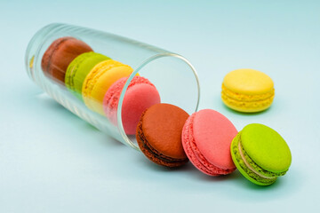 several multicolored macaron cakes in a glass cup on a blue background
