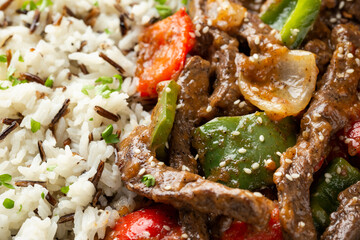 Stir fry Chinese pepper beef steak with onion, red and green bell pepper, rice in bowl