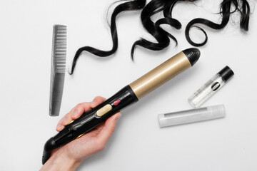 hair curler on a white background with black hair, comb and hair cosmetics