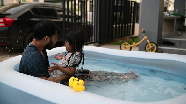 Father day concept,Asian dad and daughter use time together at home,Play in the inflatable pool